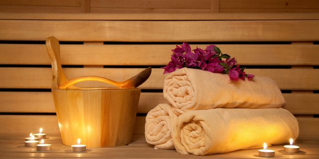 Gerollte Handtücher, Blüten und Kerzenlicht in einer Sauna