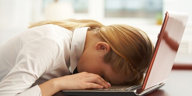 Frau legt Kopf auf Laptop-Tastatur