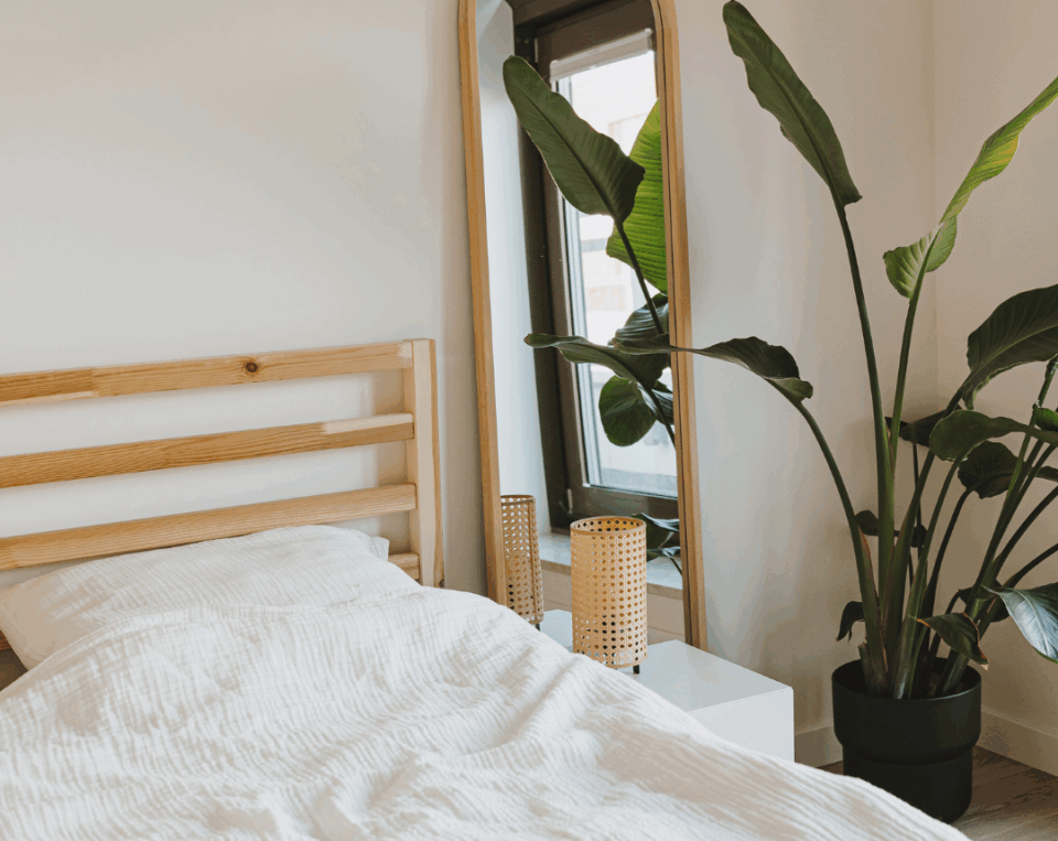 Minimalismus im Schlafzimmer: Bett mit Spiegel und Pflanze