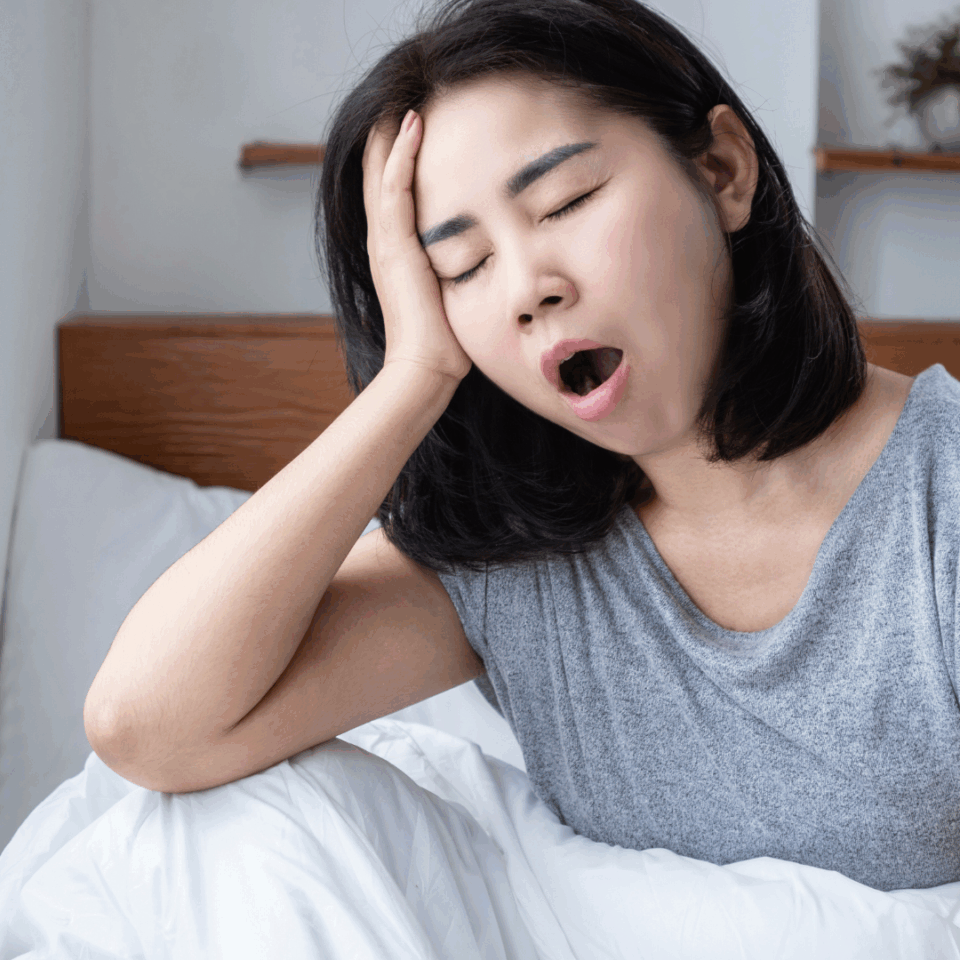 Gähnende Frau hält sich den Kopf