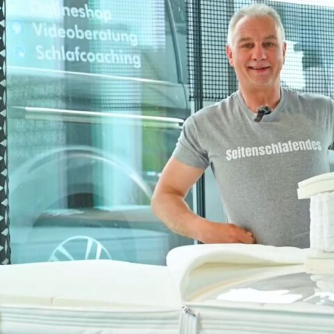 Heiko Huegel sitzt hinter Matratze und lächelt in die Kamera